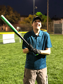Darren Keepers smiles while holding a bat over his right shoulder.